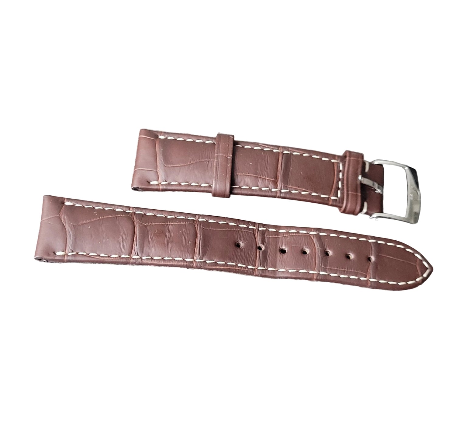 Brown leather watch strap with white stitching on a gray surface
