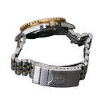 Close-up of a watch with a gold crown and silver metal band on a gray background
