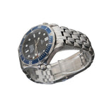 A stainless steel wristwatch with a silver-tone metal bracelet and a dark gray dial, featuring a blue bezel with white markings. The watch is displayed on a clear acrylic stand against a dark gray textured background.
