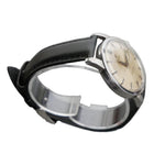Vintage watch with black strap and beige dial on a gray background